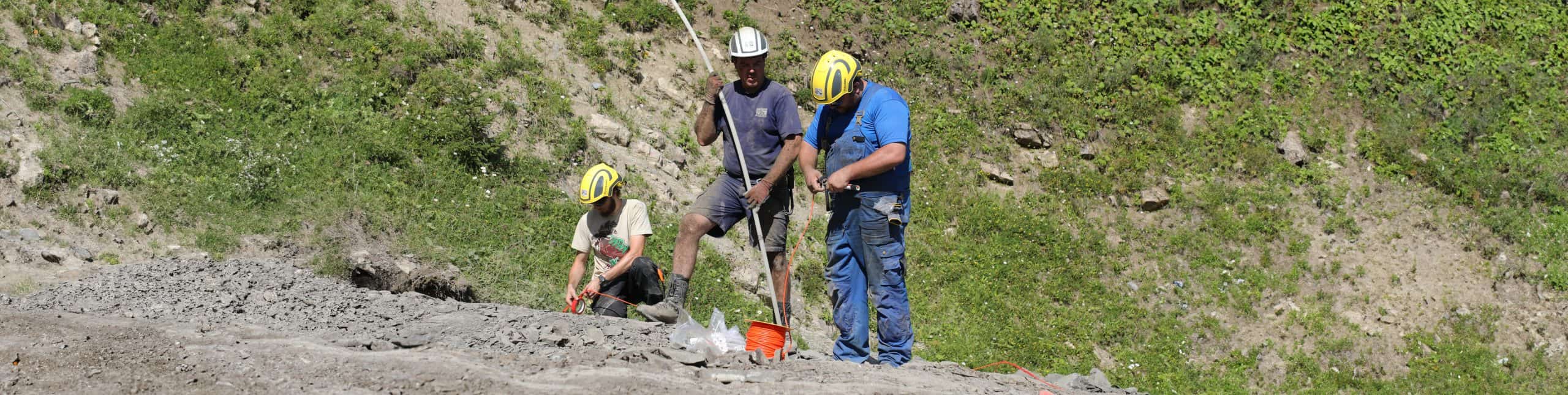 Drei Arbeiter im Steinbruch bei der Arbeit.