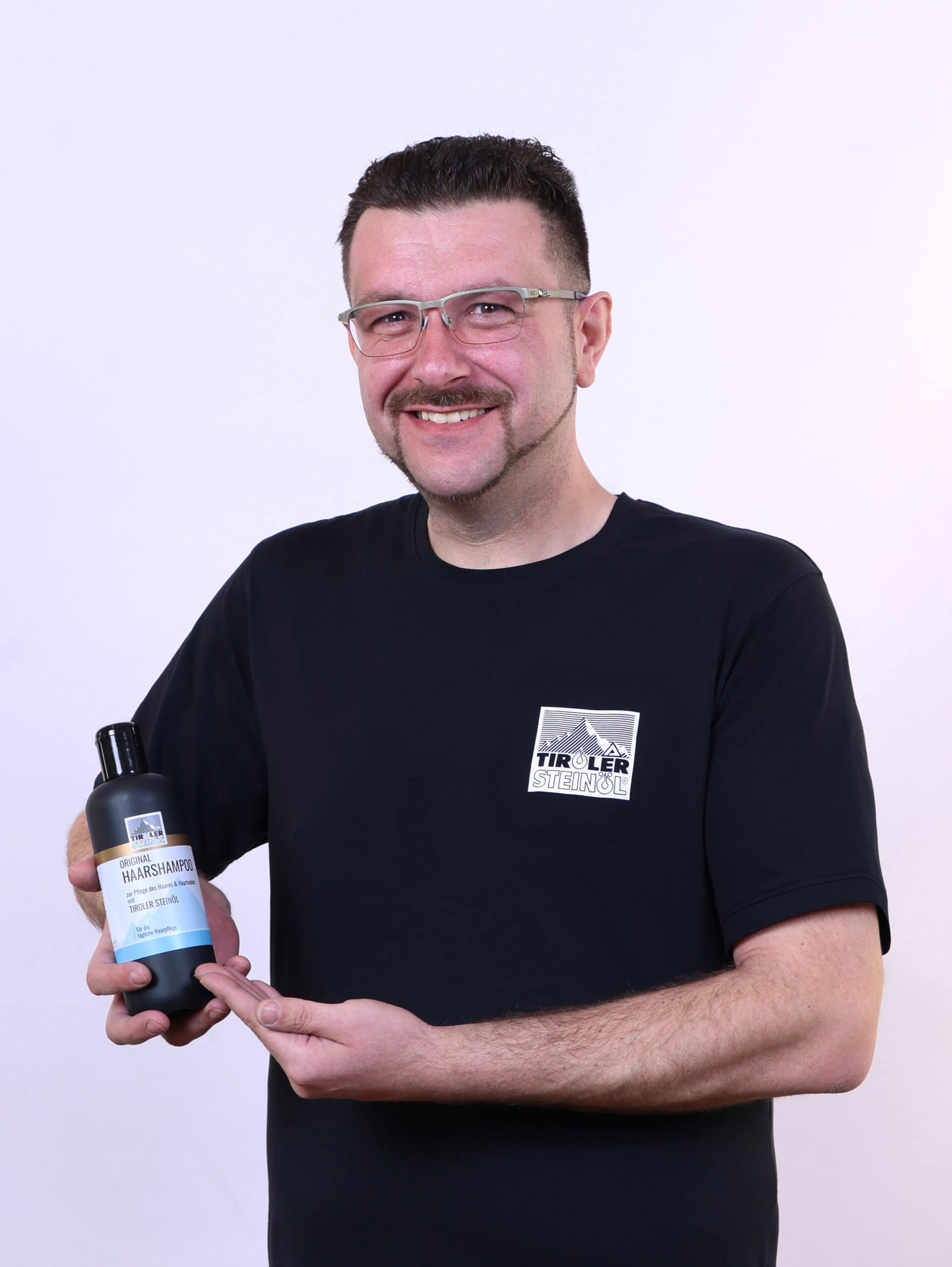 Mann präsentiert Haarshampoo in der Hand