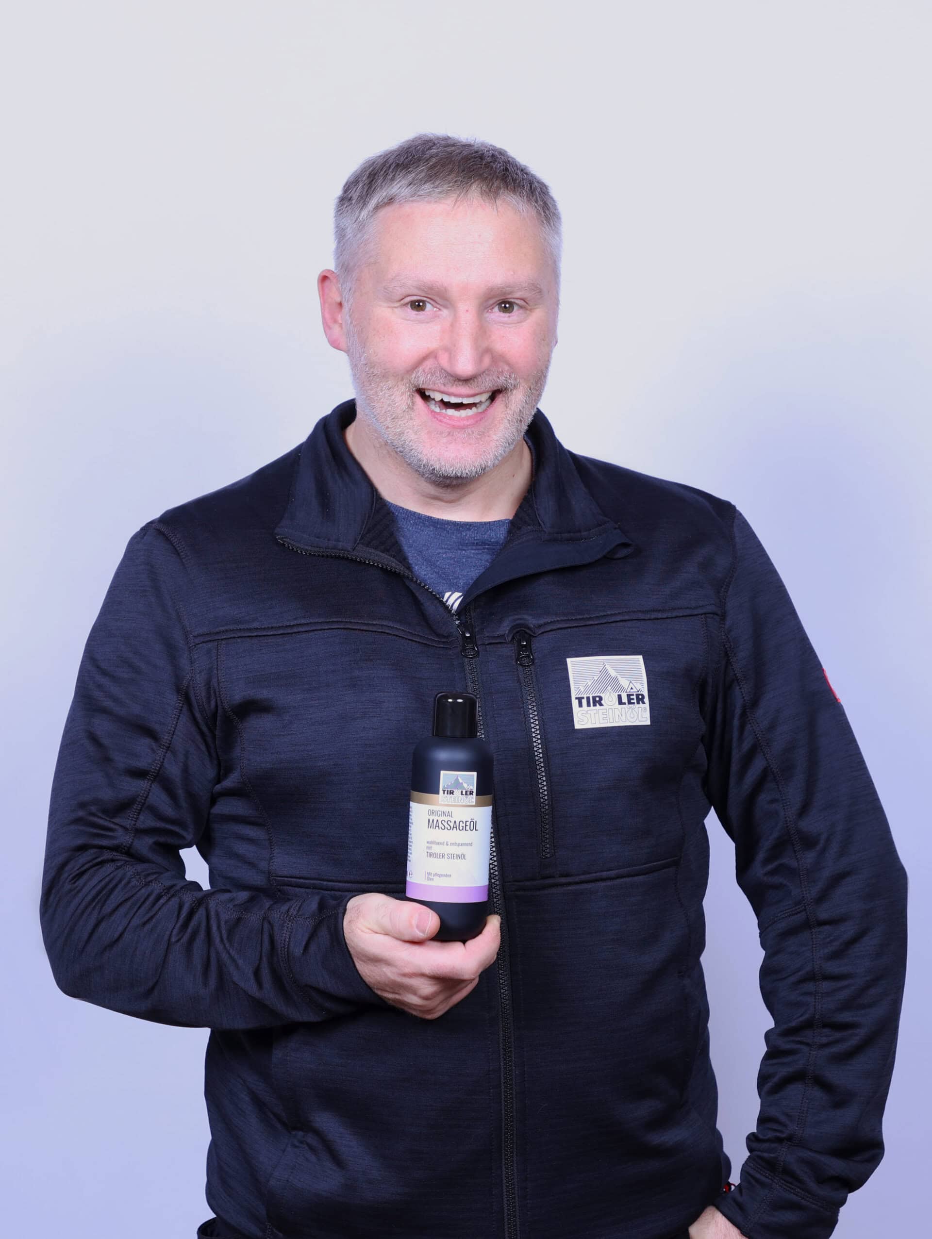 Mann präsentiert Massageöl in der Hand